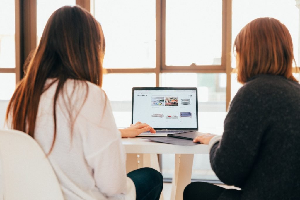 Two women redesigning a website, looking at a laptop.