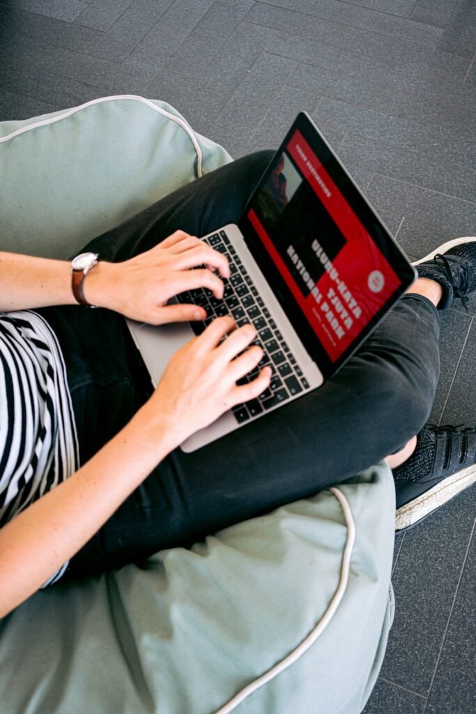A woman using a laptop on a bean bag chair while working on website projects for Agile Development LLC.
