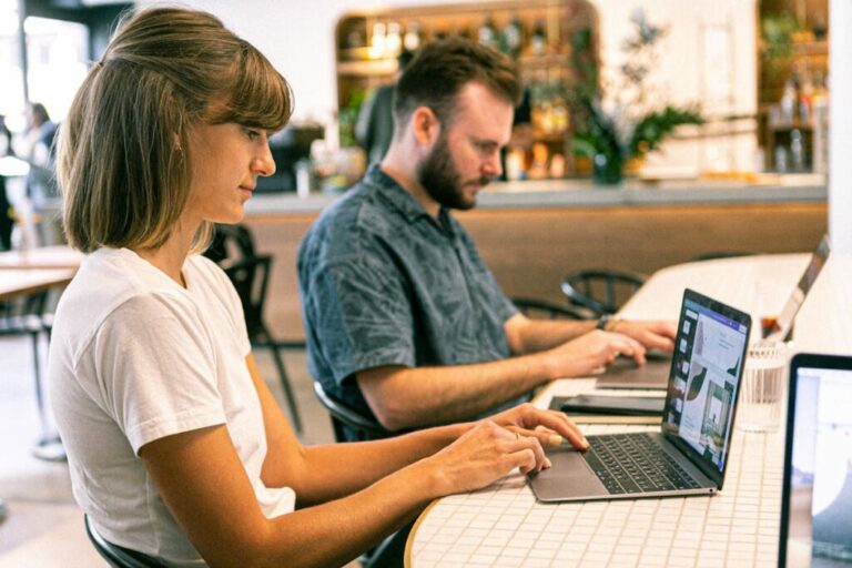 Two people working on laptops in a cafe perhaps discussing Utah website design or collaborating for Agile Development LLC