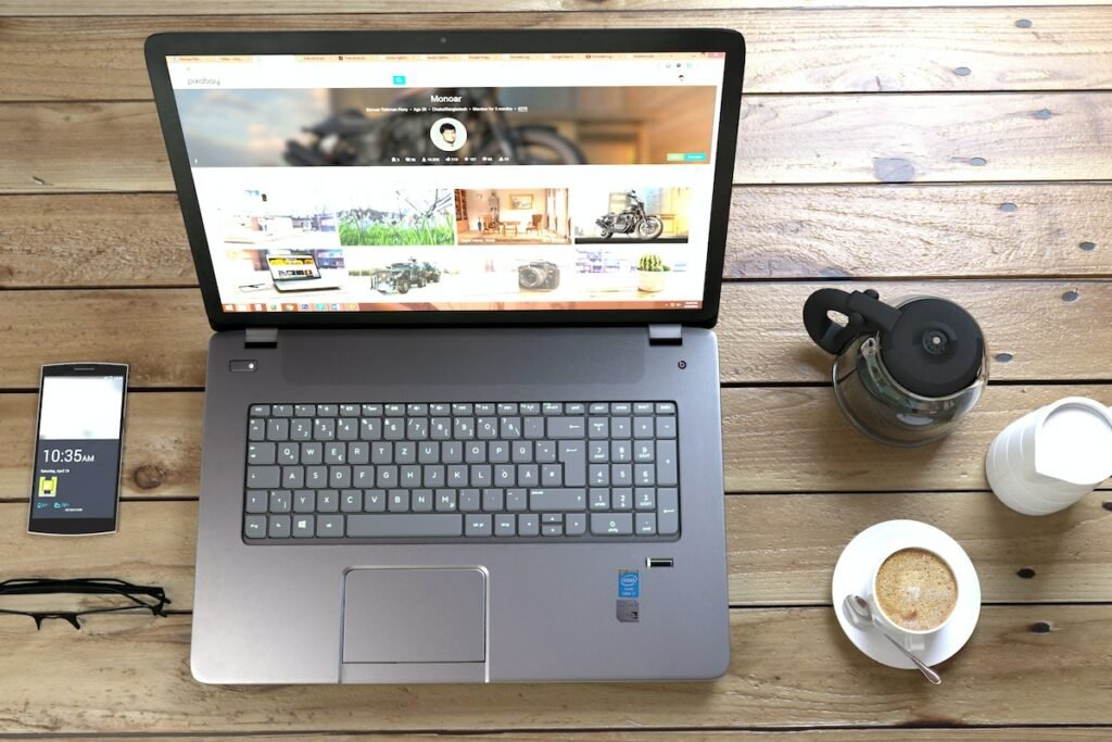 A laptop on a wooden table with a cup of coffee for Agile Development LLC, a website hosting company working on Website Projects.