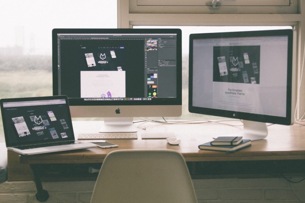 A website designer's desk with two monitors, a laptop, and a tablet.